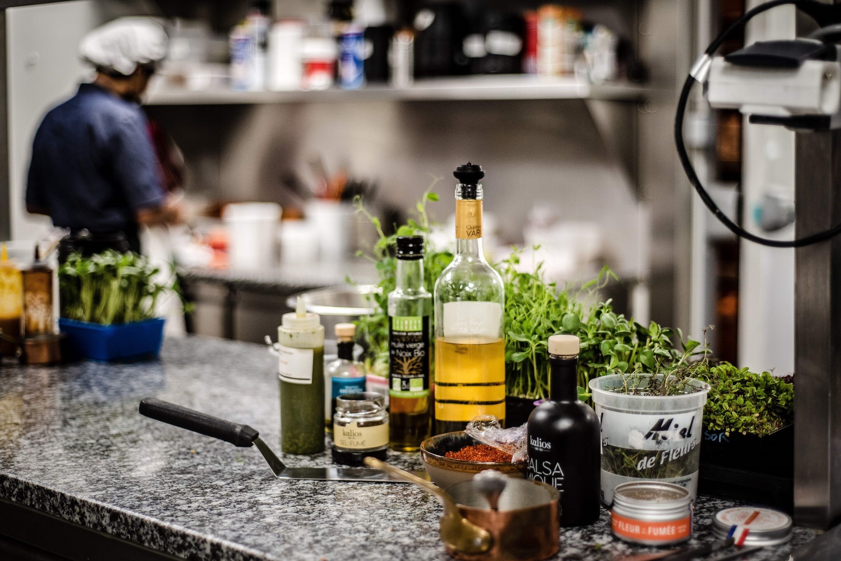 A kitchen counter with various bottles, jars, and kitchen utensils.