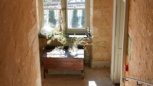 A staircase leading to a room with a window, a wooden bench, and a plant. - Hôtel de Bouilhac (Montignac)