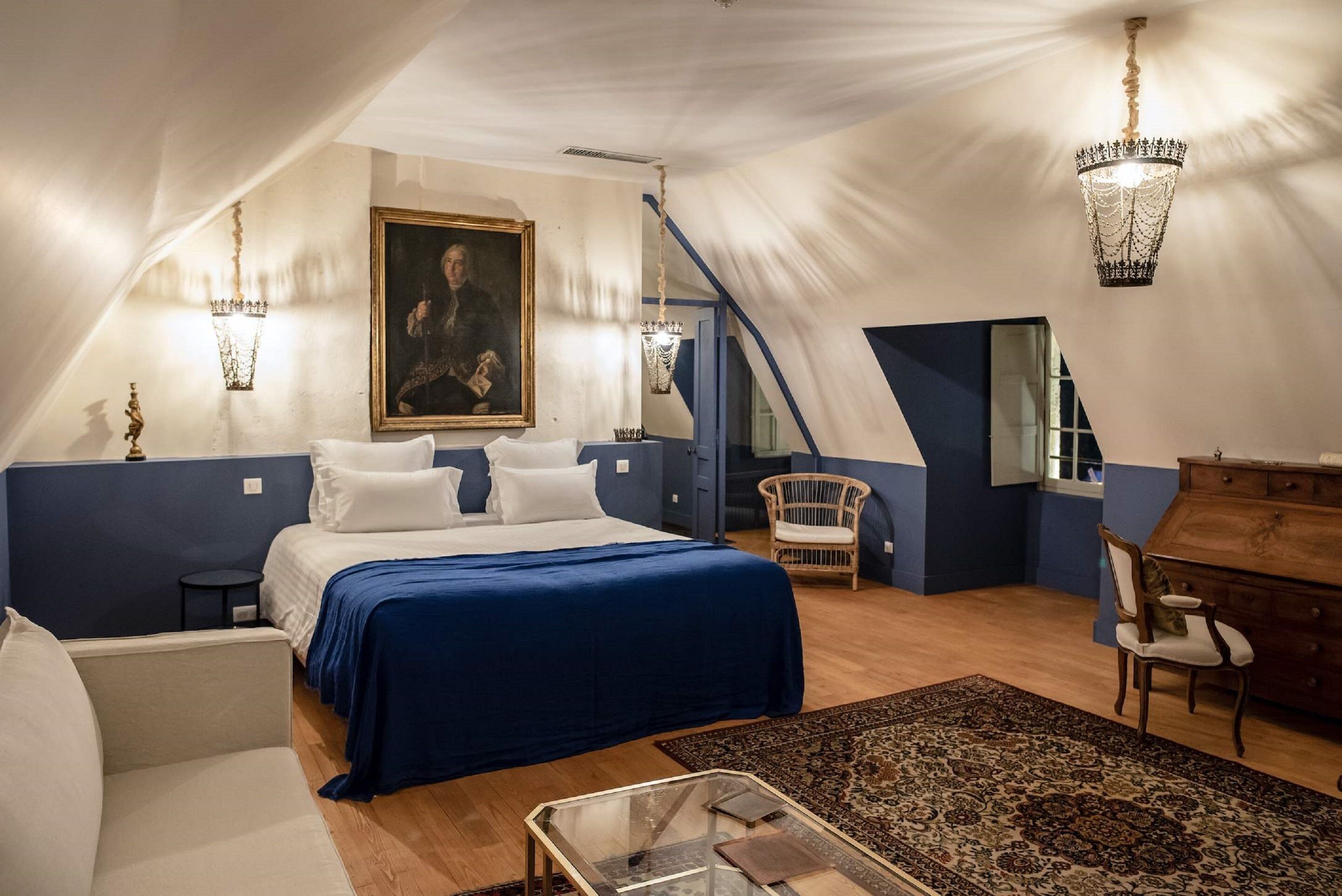 A bedroom with a large bed, a chair, a dresser, and a painting on the wall.