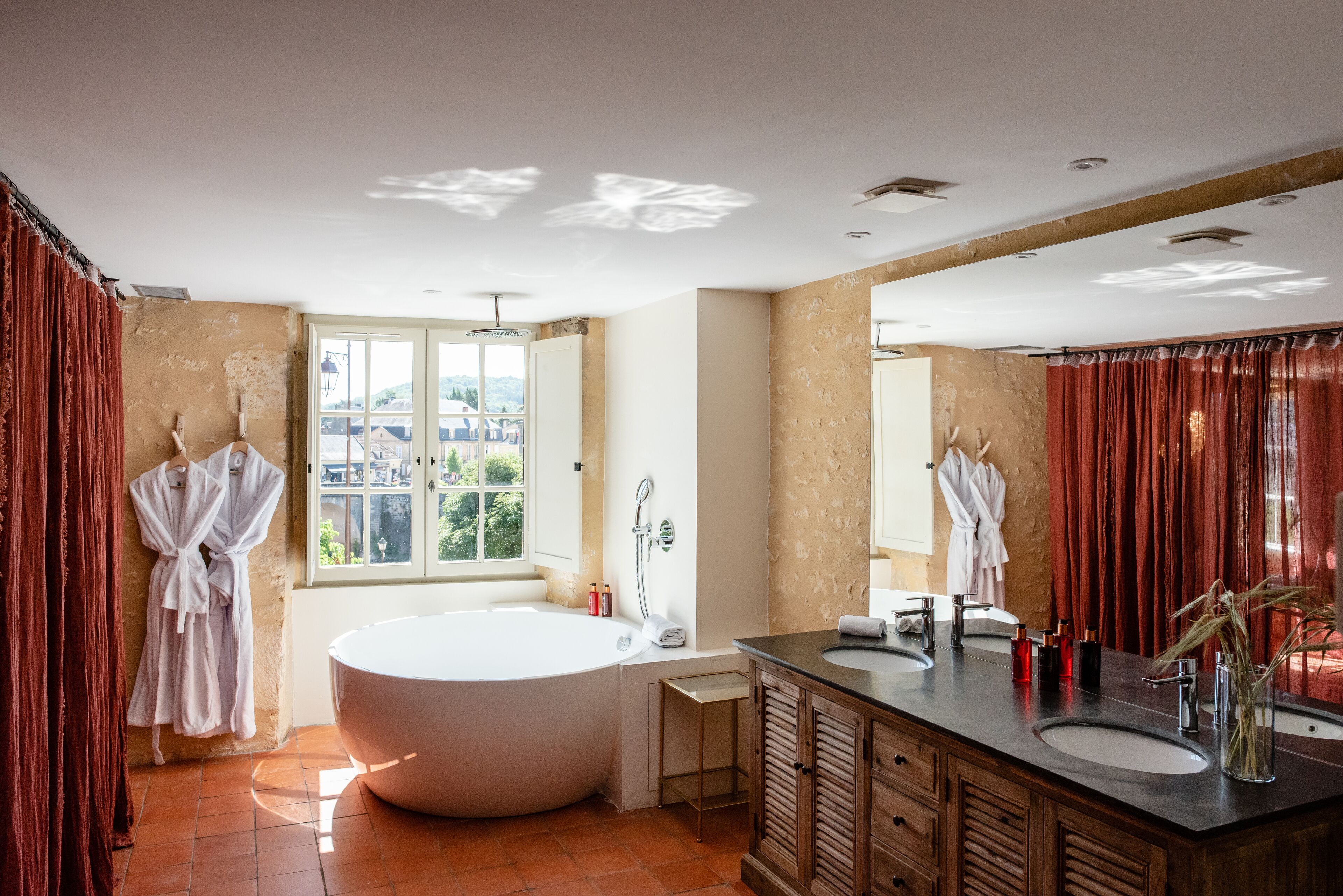 A modern bathroom with a large bathtub, dual sinks, and a vanity with a mirror.