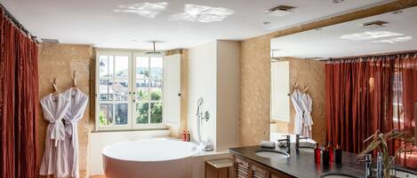 Un baño moderno con una bañera grande, lavamanos dobles y un tocador con espejo.