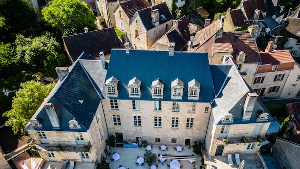 A historic building with a courtyard featuring outdoor seating and a swimming pool. - Hôtel de Bouilhac (Montignac)