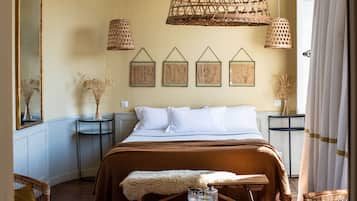 A bedroom with a large bed, two bedside tables, a mirror, and a hanging light fixture.