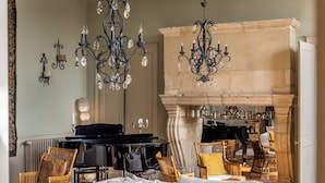 A living room with a white sofa, a glass coffee table, a piano, and a fireplace. - Hôtel de Bouilhac (Montignac)