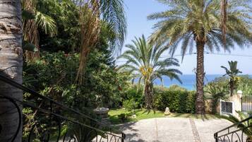A paved pathway leading to a gated entrance with a view of the sea.