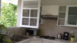 A kitchen with white cabinets, a microwave, a stove, and a sink.