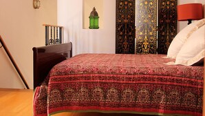 Un dormitorio con una cama grande, un aparador de madera, un farol verde y un espejo montado en la pared.
