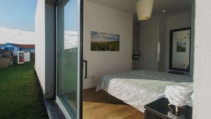 Un dormitorio con cama, mesita de noche, espejo y ventana.