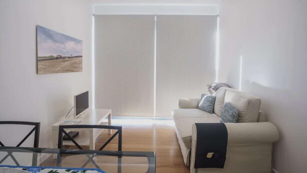 Una sala de estar moderna con un sofá, una mesa de centro de vidrio y un televisor.