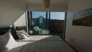 Un dormitorio con una cama grande, vistas al exterior y un cuadro en la pared.
