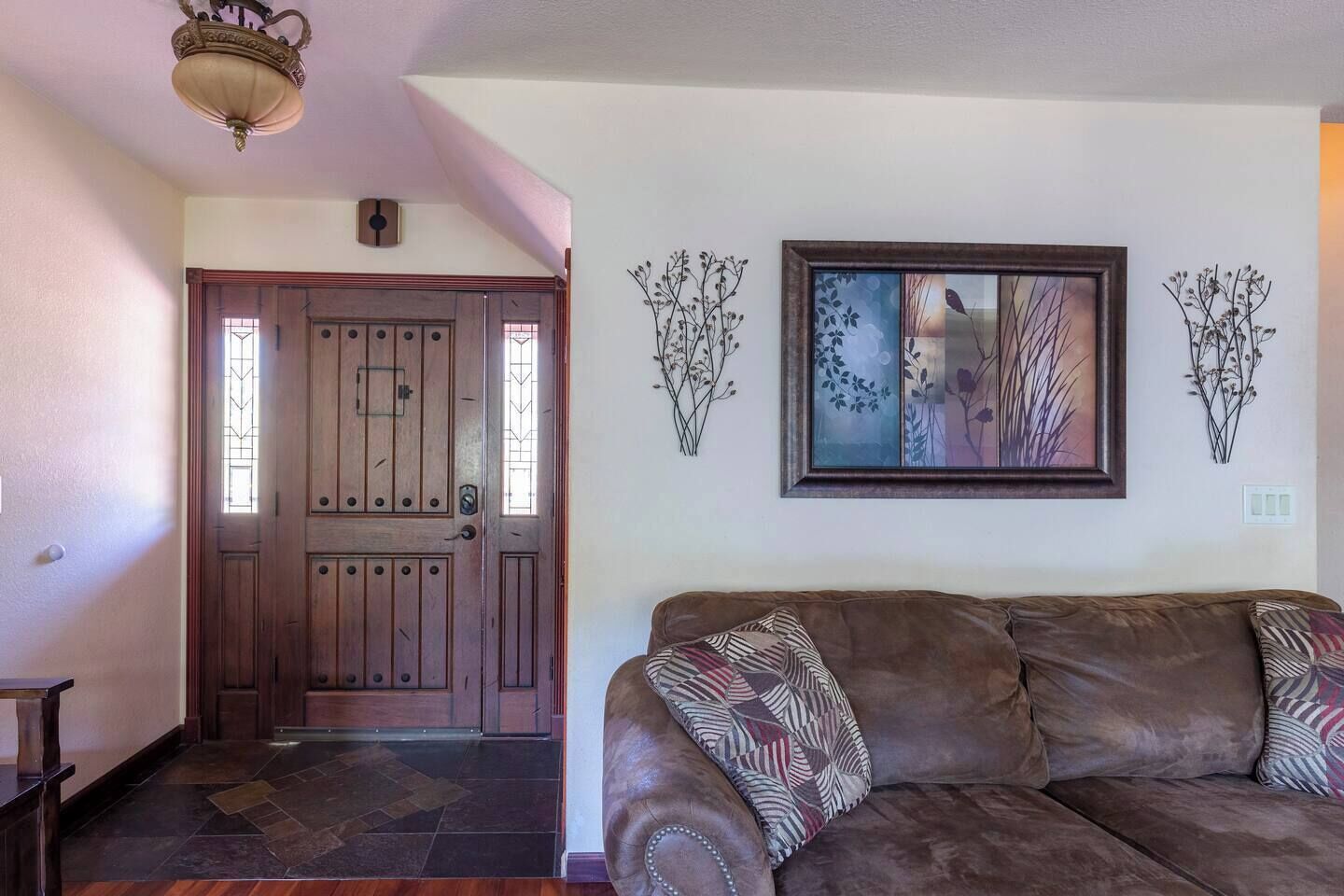 Uma sala de estar com um sofá de couro marrom, uma porta de madeira e uma obra de arte emoldurada na parede.