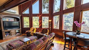 A spacious living room with a large TV, comfortable seating, and a dining area with a table and chairs.