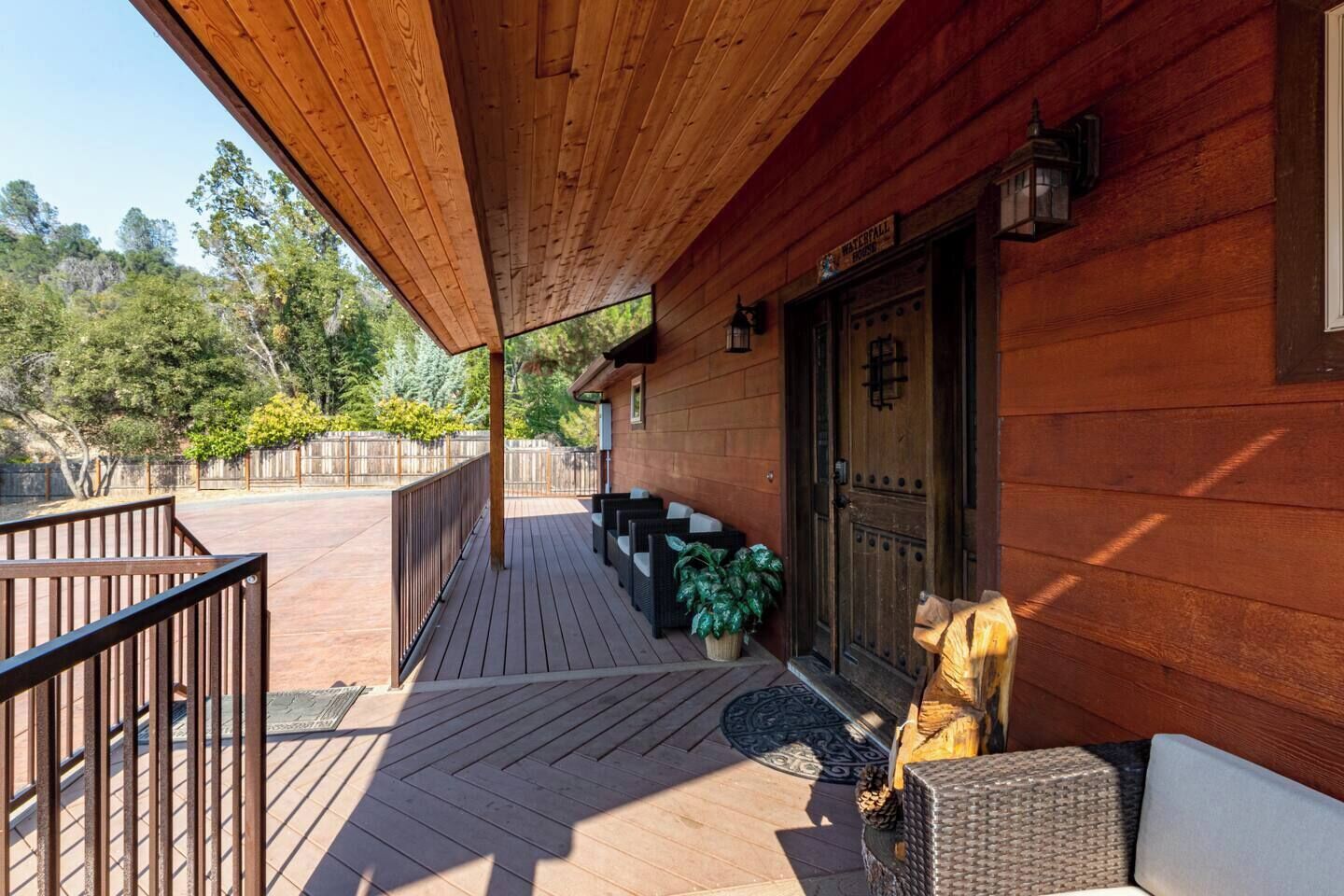 A wooden deck with outdoor seating, a wooden door, and a sign reading "Waterfall House."