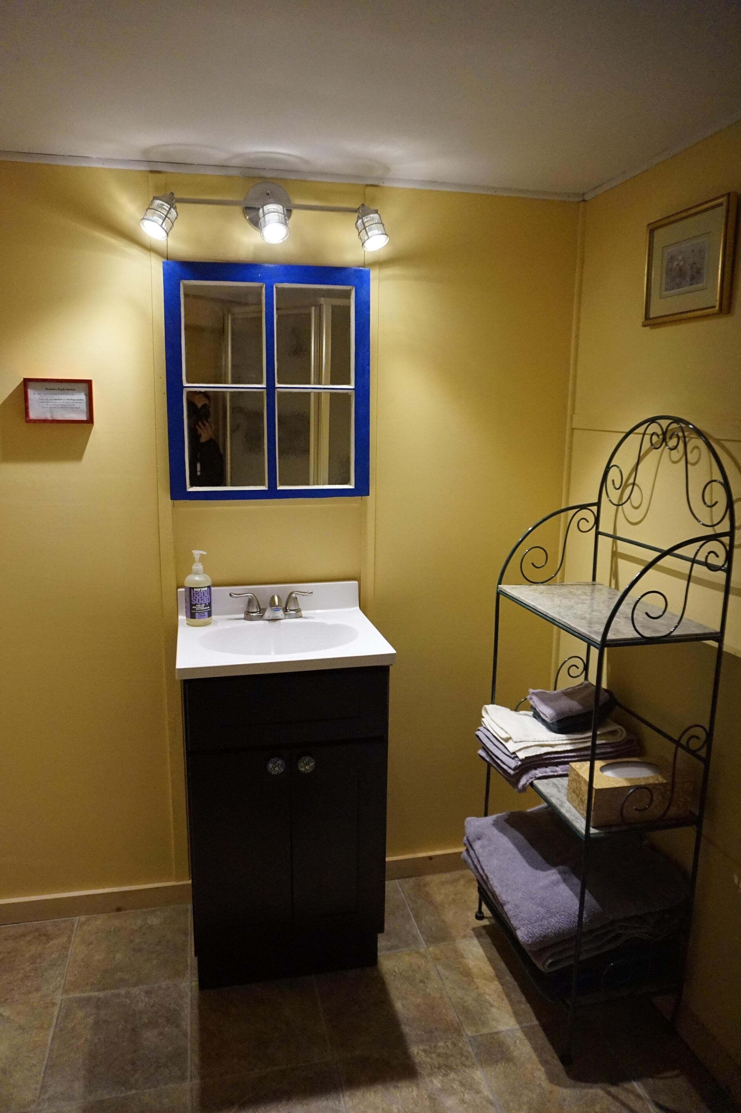 Une salle de bain avec un lavabo, un miroir et une étagère où sont rangées les serviettes.