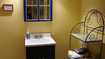 Une salle de bain avec un lavabo, un miroir et une étagère où sont rangées les serviettes.