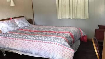 A bedroom with a bed, a nightstand, a lamp, and a window with curtains.