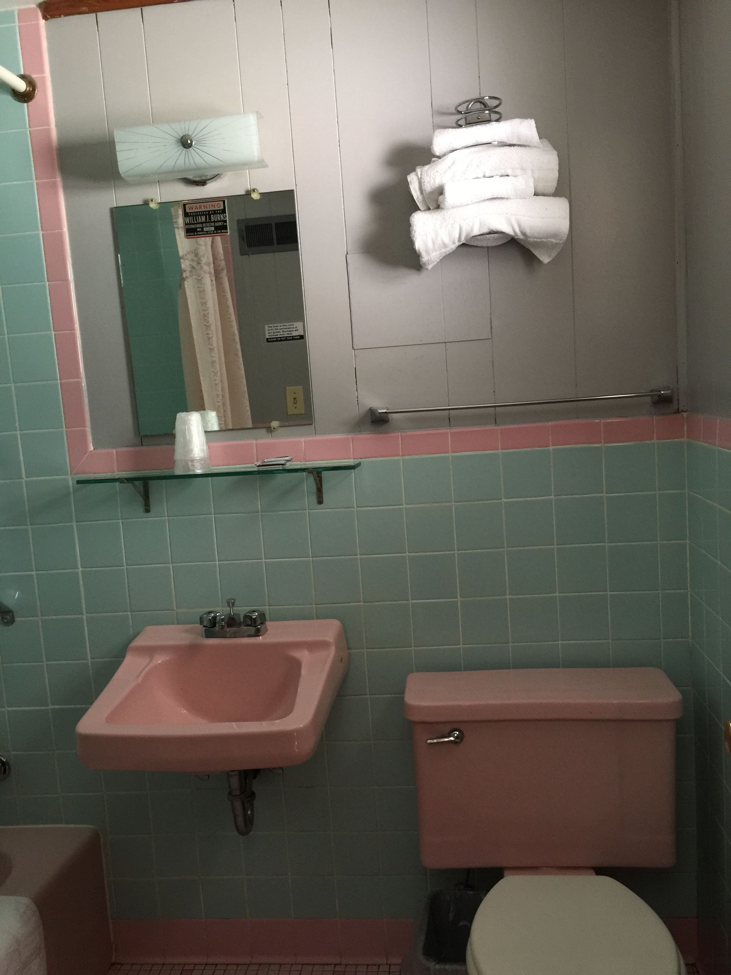 A bathroom with a pink sink, a toilet, and a mirror above the sink.