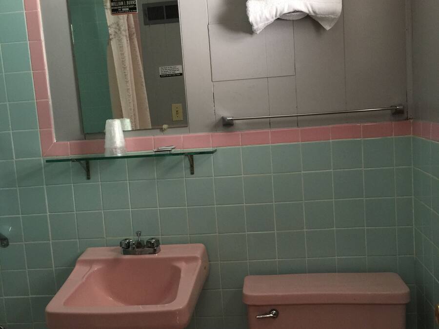 A bathroom with a pink sink, a toilet, and a mirror above the sink.