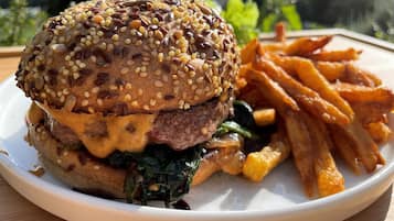 A plate with a burger, fries, and greens.