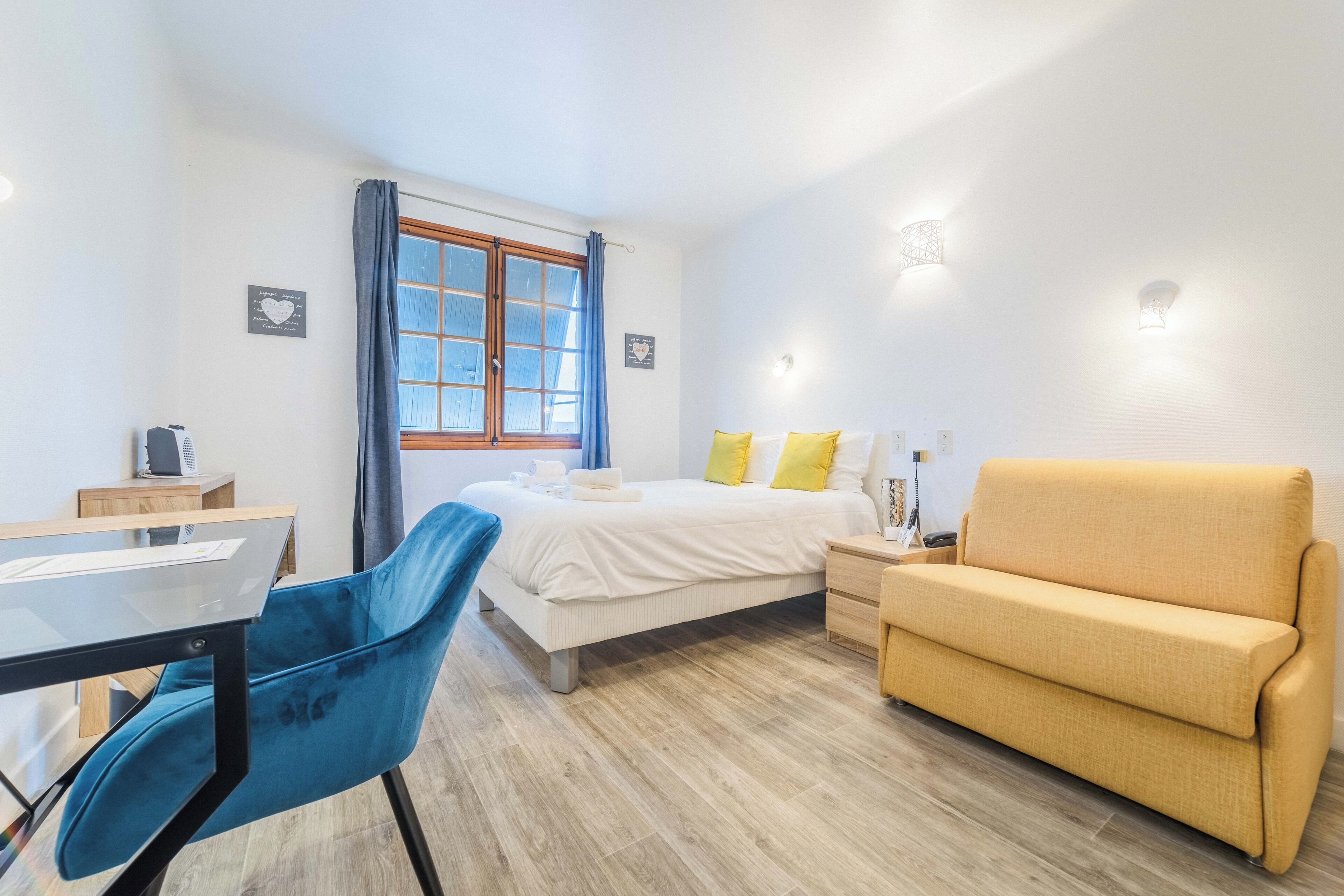 A bedroom with a bed, a sofa, a desk, and a chair.