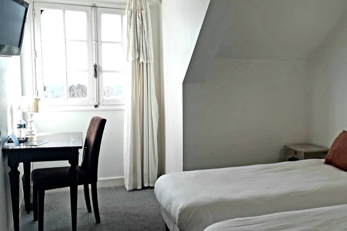 A hotel room with two beds, a desk, and a chair.