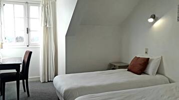 Ein Hotelzimmer mit zwei Betten, einem Schreibtisch und einem Stuhl.