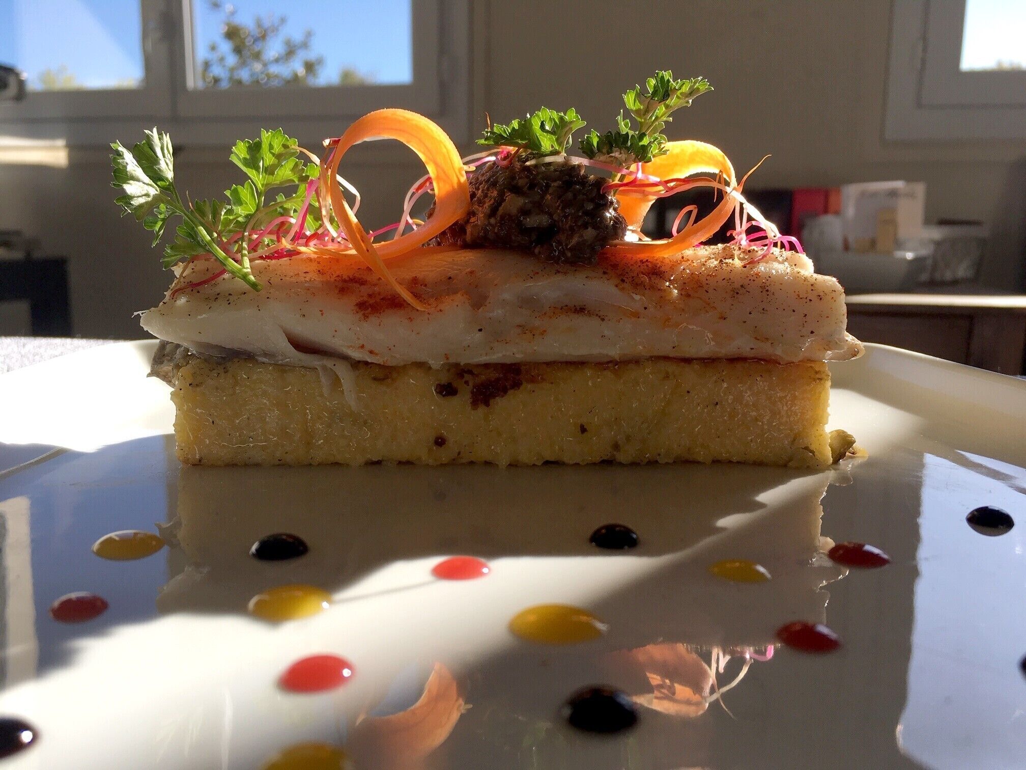 Un dessert servi dans une assiette blanche, décorée de points de couleurs vives.