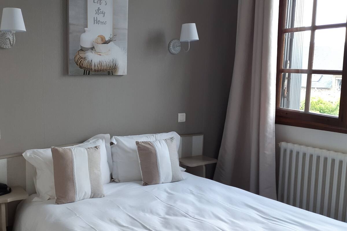 A bedroom with a bed, bedside tables, lamps, and a window.