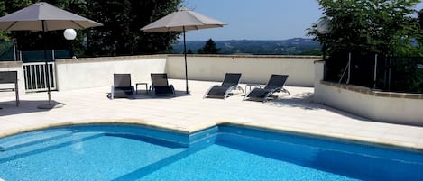 Una piscina al aire libre, sillones reclinables de piscina