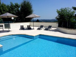 Una piscina al aire libre, sillones reclinables de piscina