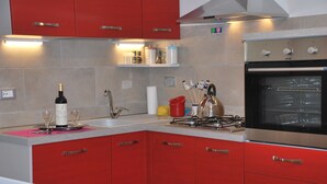 A kitchen with red cabinets, a gas stove, and an oven. - A wonderful country house in the heart of Chianti (Panzano In Chianti)