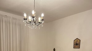 A bedroom with a large bed, a chandelier, a nightstand, and a wall-mounted light fixture. - A wonderful country house in the heart of Chianti (Panzano In Chianti)