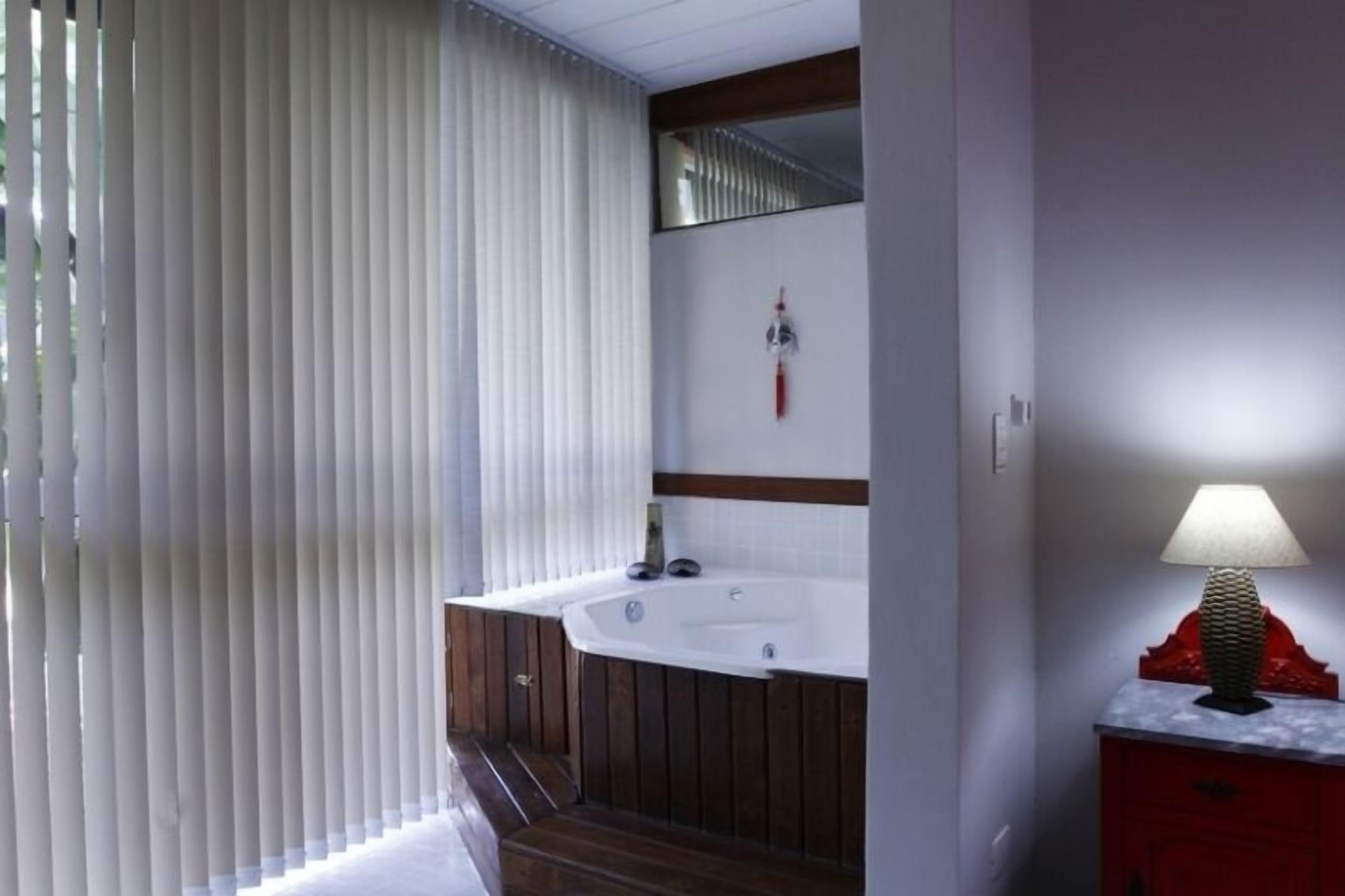 Ein Badezimmer mit einem Holz-Waschtisch, einer weißen Badewanne und einer roten Lampe.