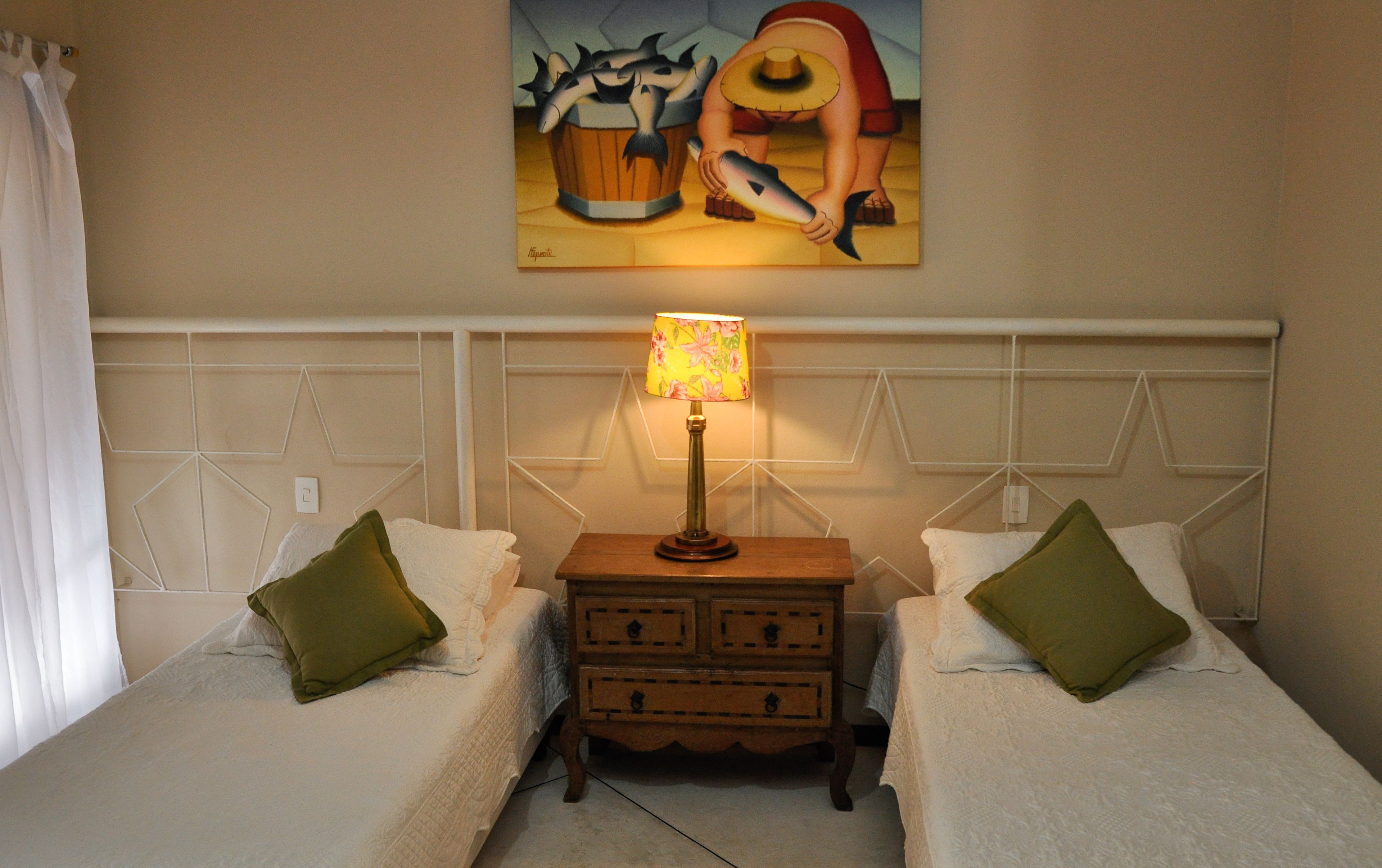 A hotel room with two beds, a nightstand with a lamp, and a painting on the wall.