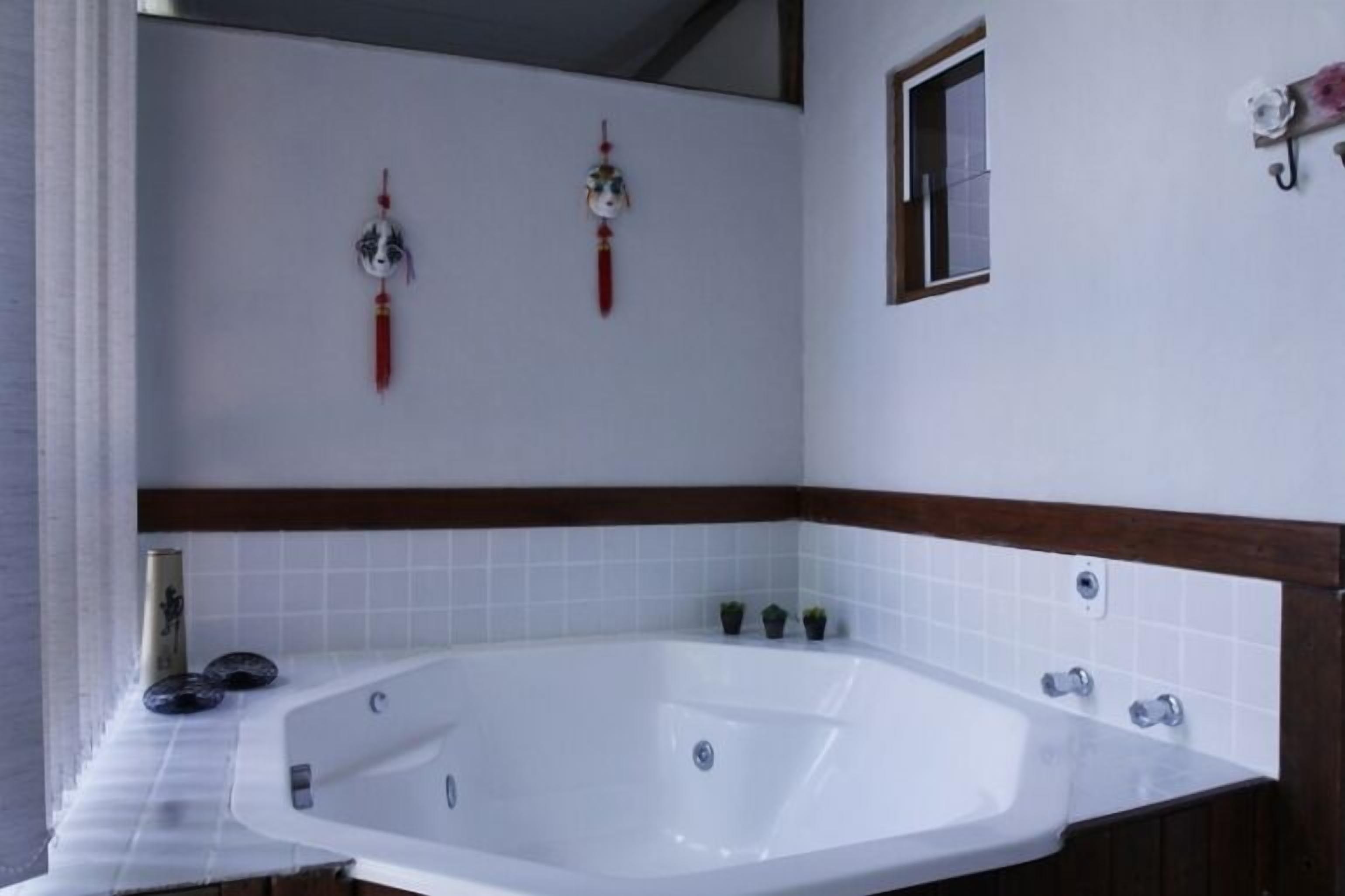 Ein Badezimmer mit einer großen Badewanne, einem kleinen Fenster und dekorativen Wandgestaltungen.