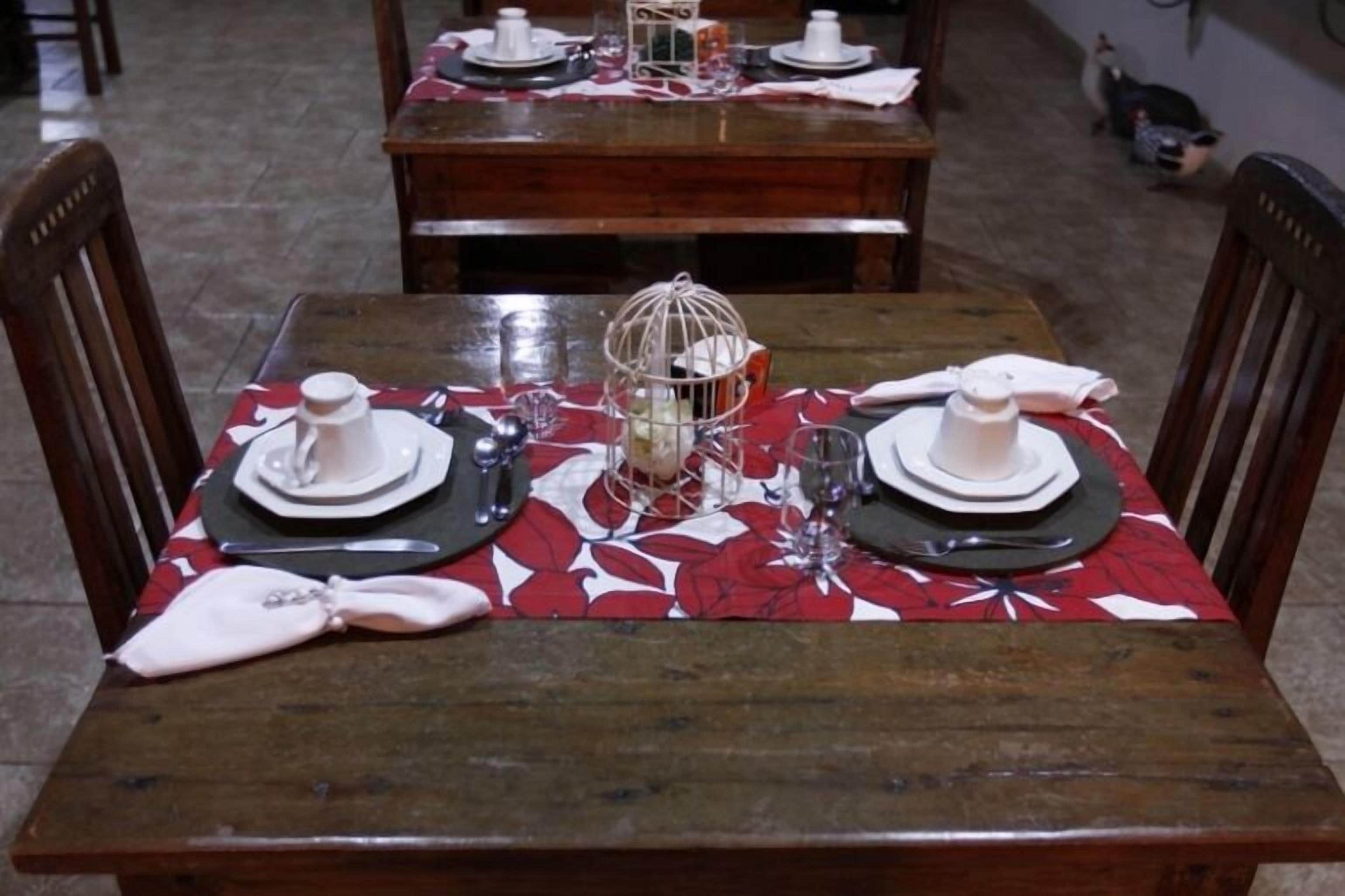 Een eettafel gedekt met borden, bestek en een decoratieve vogelkooi als middelpunt.