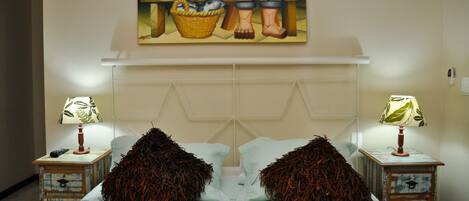 A bedroom with a bed, two nightstands with lamps, a painting above the bed, and a headboard.