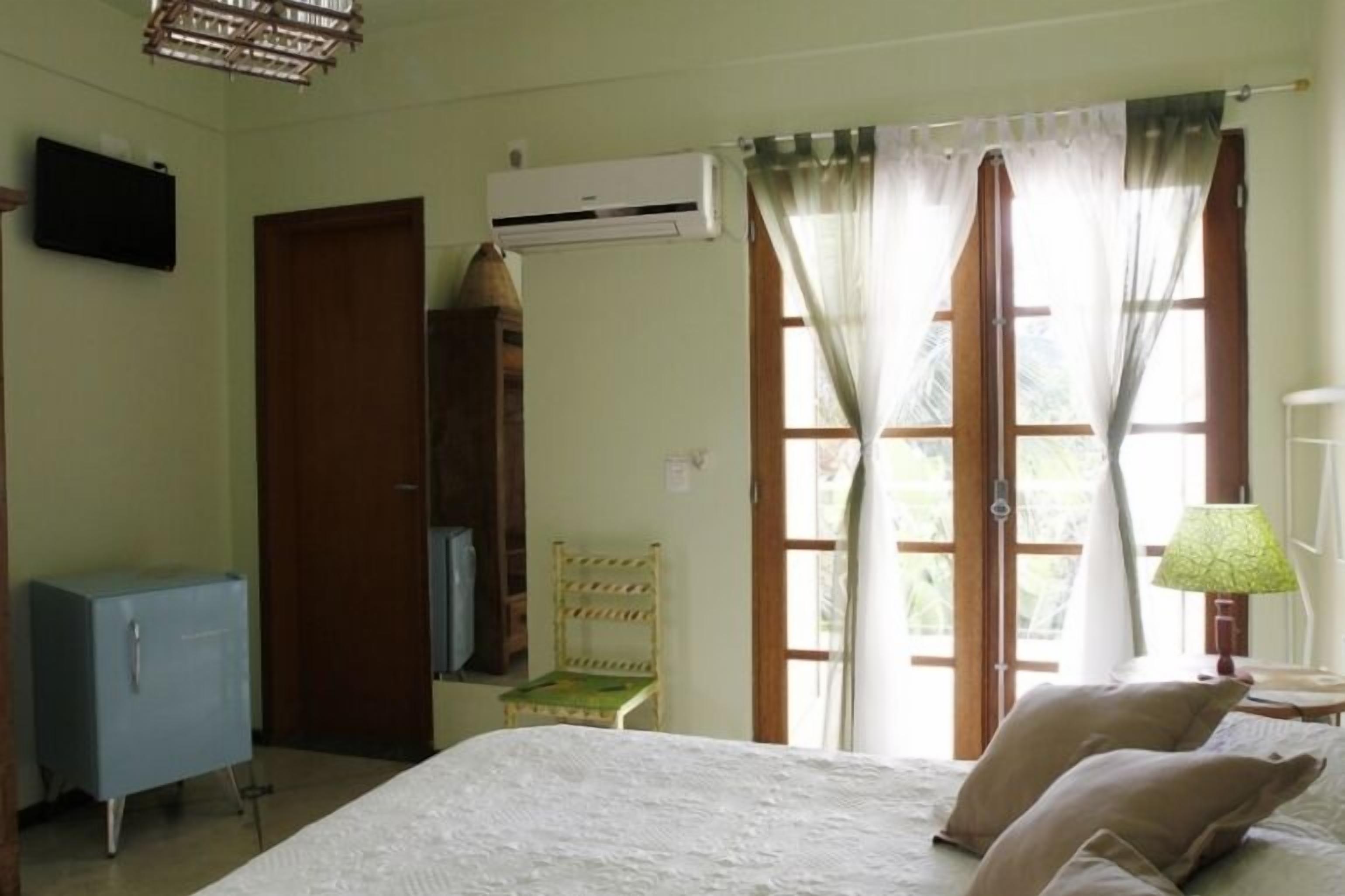 A room with a bed, a chair, a desk, a lamp, and a television.
