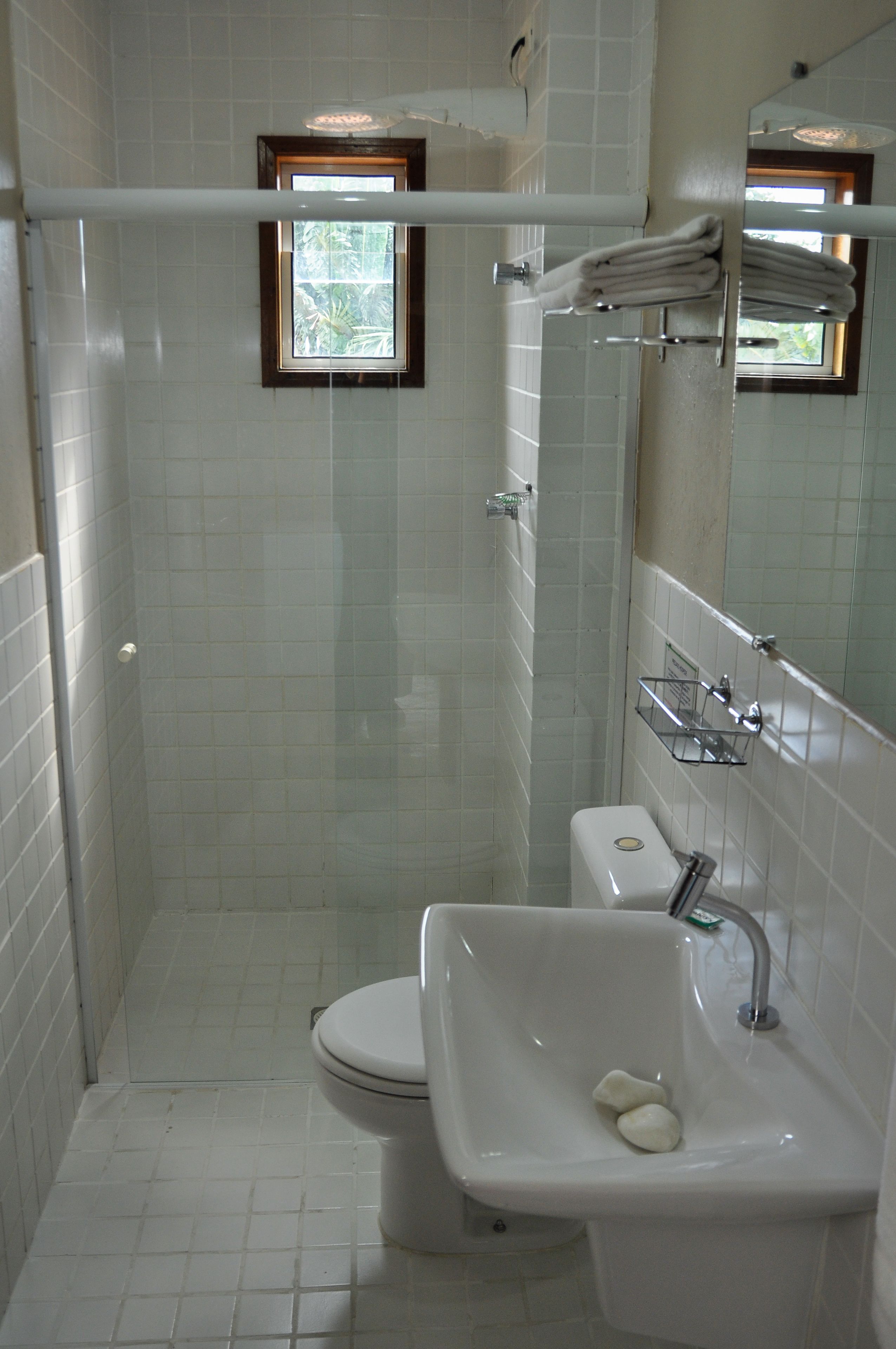 A small, tiled bathroom with a toilet, sink, and shower.
