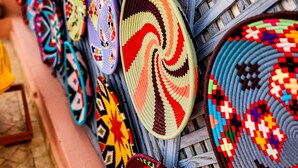 A collection of intricately woven mats displayed on a wooden rack. - Dar Chadia (Marrakech)