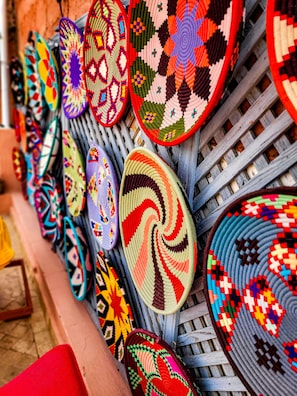 A collection of intricately woven mats displayed on a wooden rack. - Dar Chadia (Marrakech)