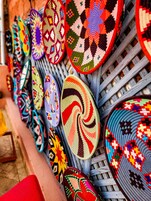Una colección de esteras intrincadamente tejidas exhibidas en un estante de madera.