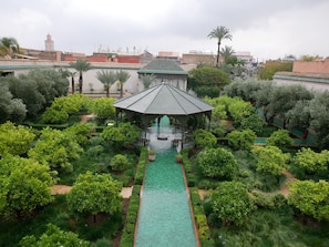 A lush garden with a central water feature, a gazebo, and a view of surrounding buildings. - Dar Chadia (Marrakech)