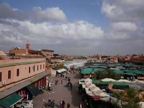 A bustling outdoor market with various stalls and people. - Dar Chadia (Marrakech)
