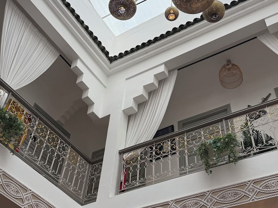 Un atrio de varios niveles con barandillas ornamentales, luces esféricas colgantes y techo de cristal.