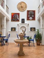 Una habitación con una fuente, sillas azules y obras de arte en las paredes.