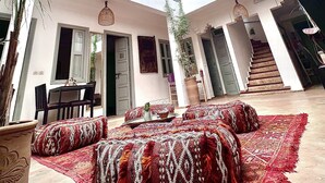 Un vaste atrium doté d’un haut plafond, un espace de détente central agrémenté de coussins à motifs et un escalier menant à un niveau supérieur.