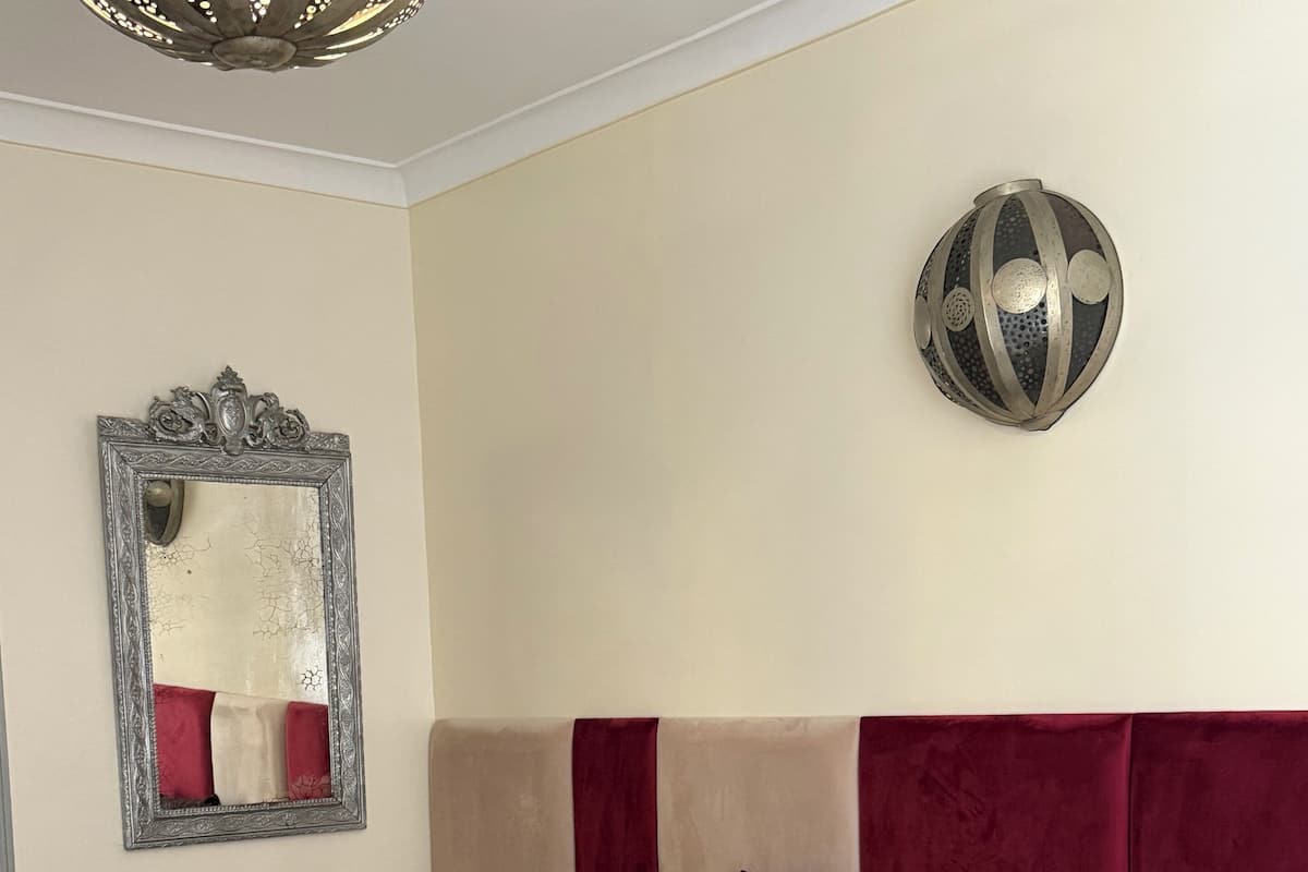 A hotel room with a large bed, a nightstand, a mirror, and a decorative wall piece.