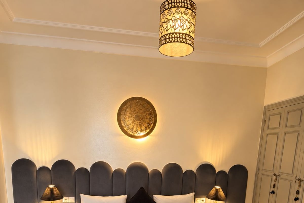 A hotel room with a large bed, two bedside lamps, a decorative wall light, and a wardrobe.