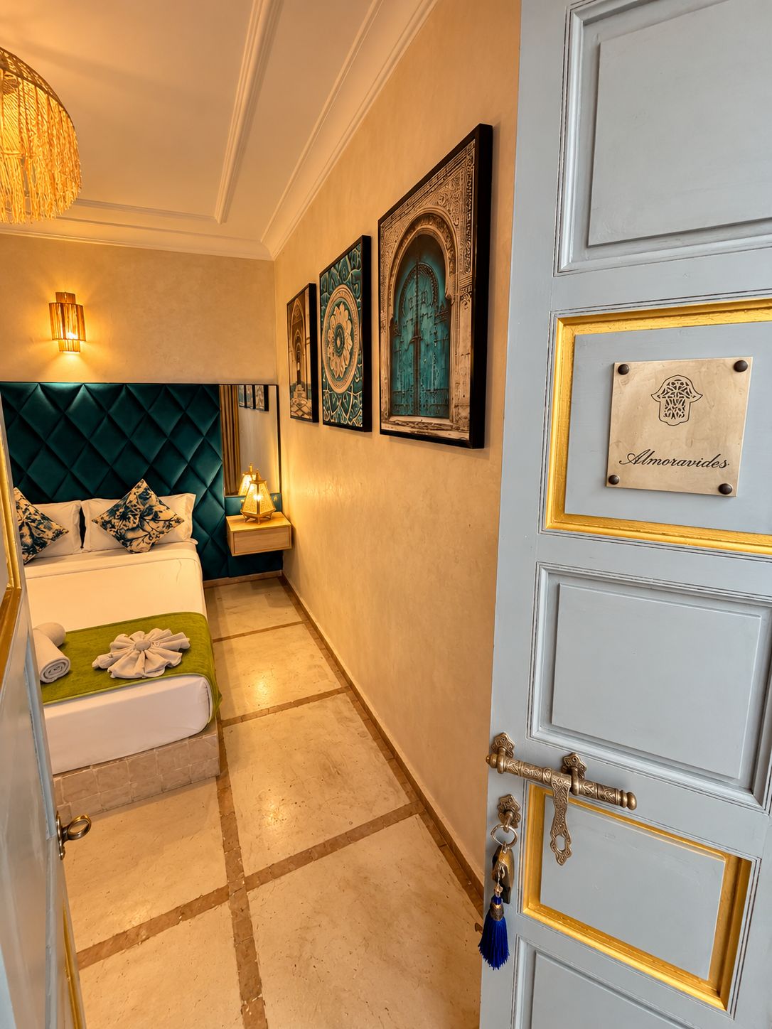 A hotel room with a bed, a nightstand, a wall-mounted lamp, and artwork.
